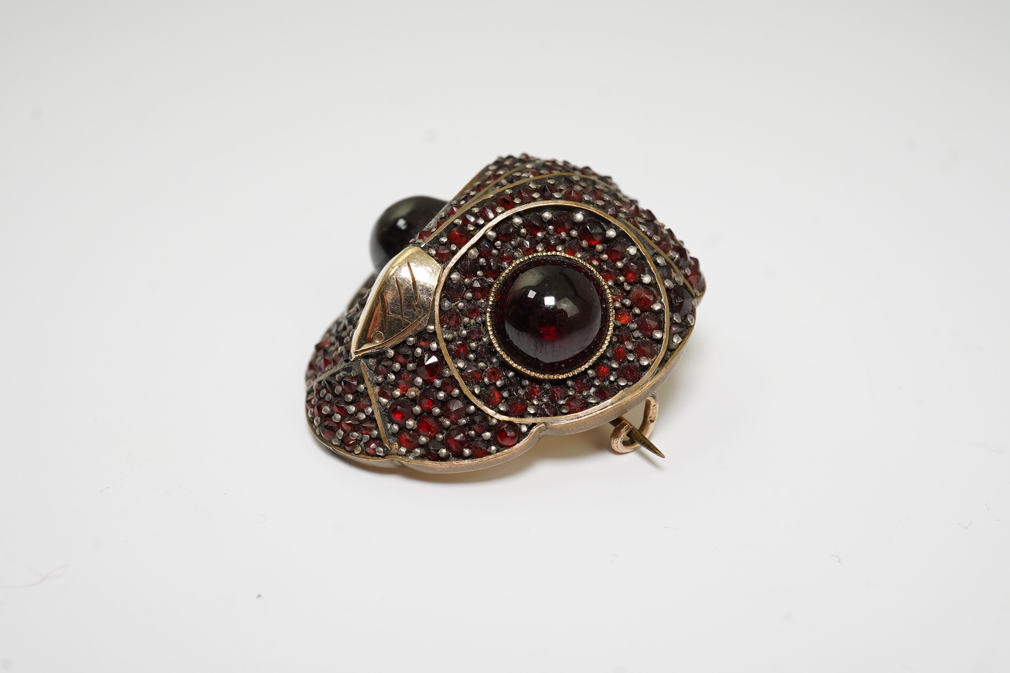 A Victorian gold overlaid base metal and pave set garnet owl's head brooch